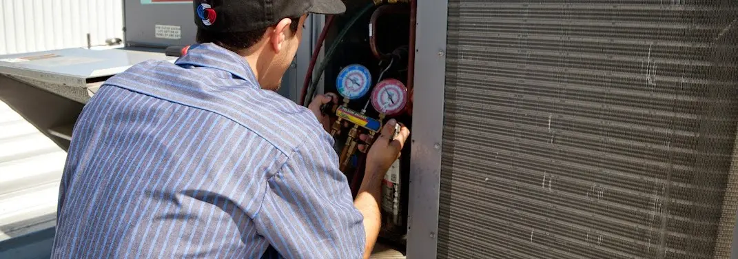 HVAC technician servicing a condenser unit in Damascus